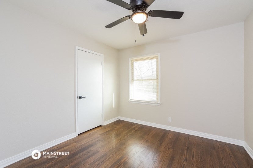 a bedroom with white walls and a ceiling fan