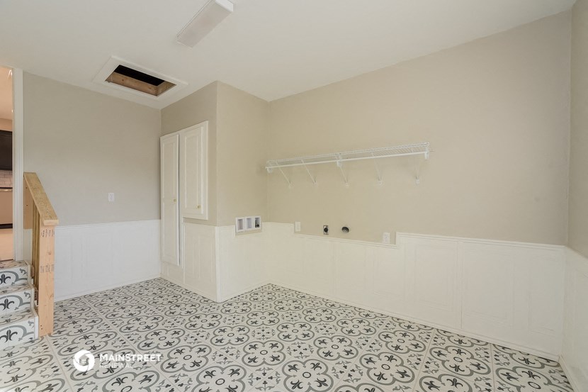 a laundry room with white walls and a tiled floor
