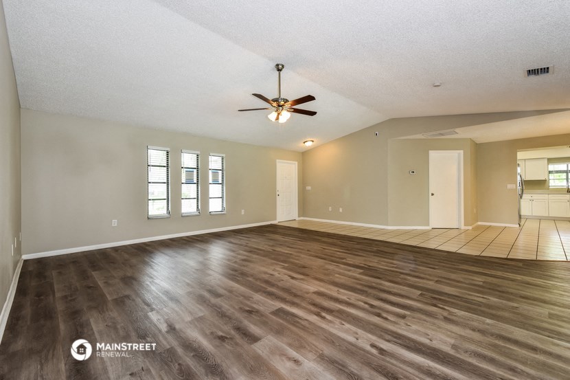 the living room and dining room of an empty house with a ceiling fan
