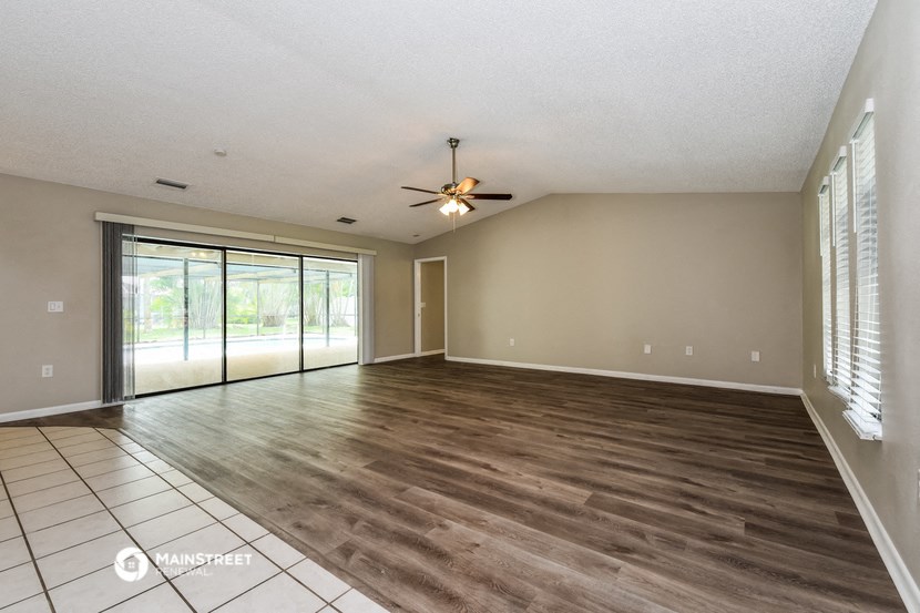 an empty living room with a ceiling fan and sliding glass doors