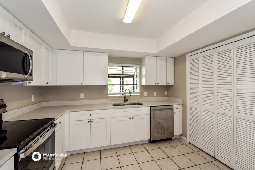 a kitchen with white cabinets and a sink and a window