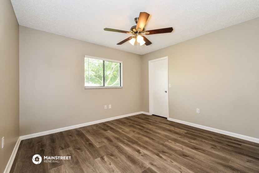 the spacious living room with wood flooring and a ceiling fan