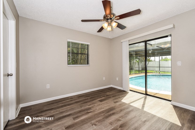an empty living room with a ceiling fan and a pool