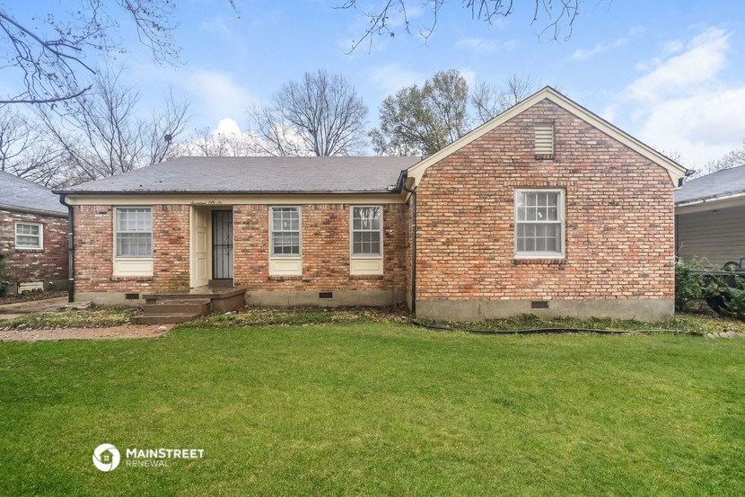 the front of a brick house with a green lawn