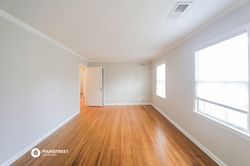 an empty living room with wood flooring and a window