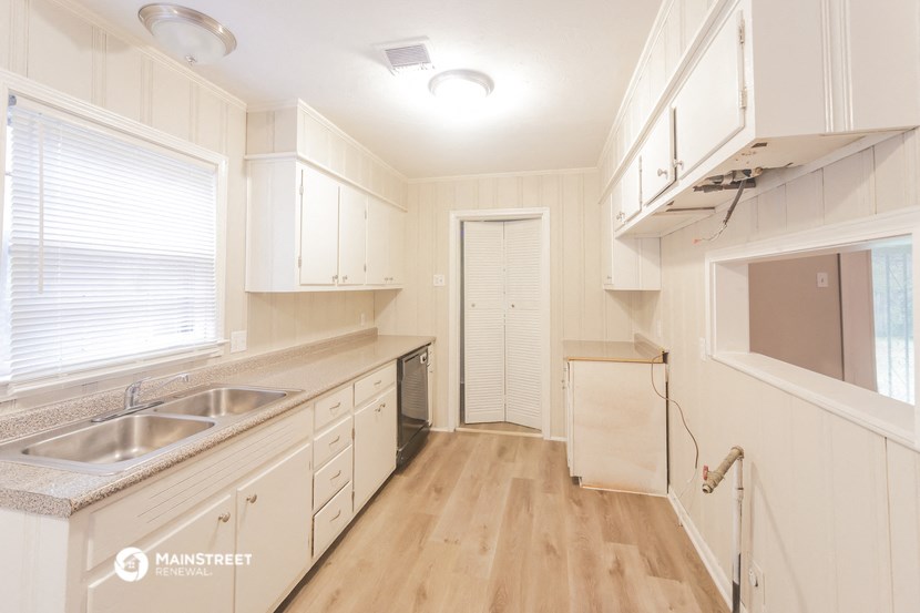 a kitchen with white cabinets and a sink and a window