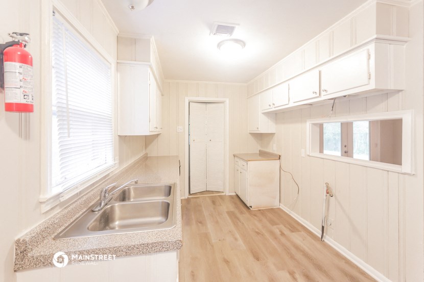 a white kitchen with a sink and a window