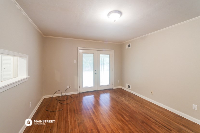a living room with a hardwood floor and a door to a balcony