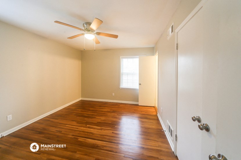 an empty room with wood floors and a ceiling fan