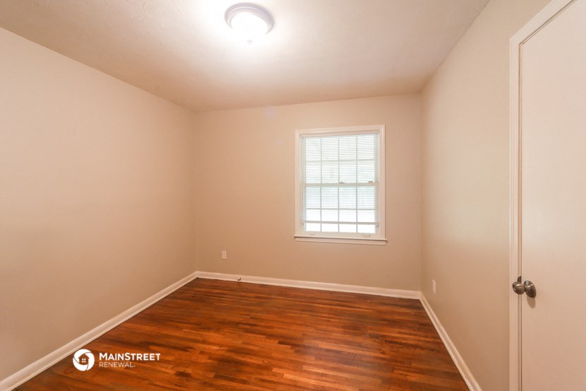 a bedroom with a hard wood floor and a window