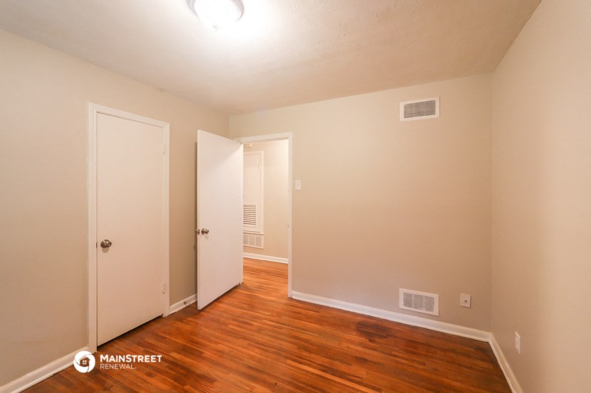 a bedroom with wood flooring and a door to a closet