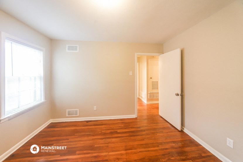 the living room of an empty house with wood floors and a white door