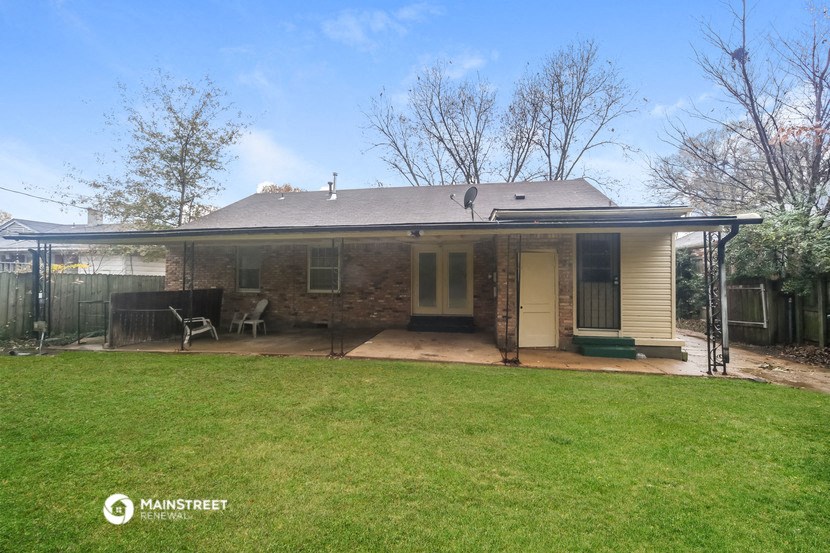 a small brick house with a yard and a screened in porch
