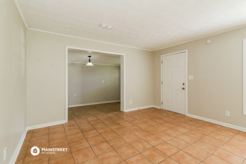 an empty living room with tile flooring and a door to a closet