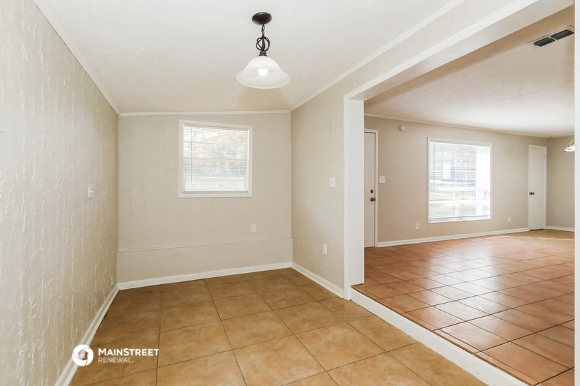 an empty dining room with tile flooring and a ceiling light
