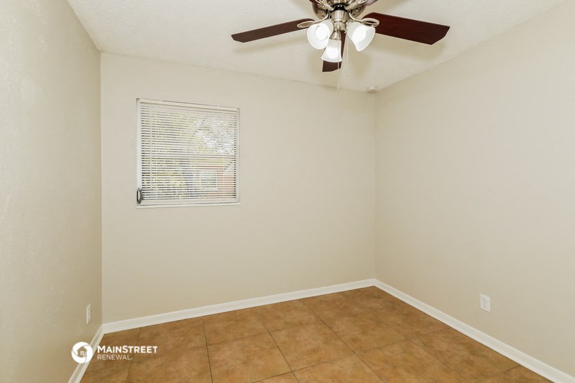 the living room of this home has a ceiling fan and a tiled floor