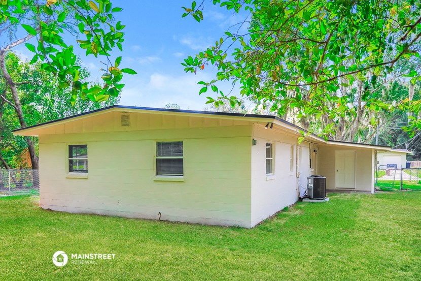 a small white house with a yard and a tree