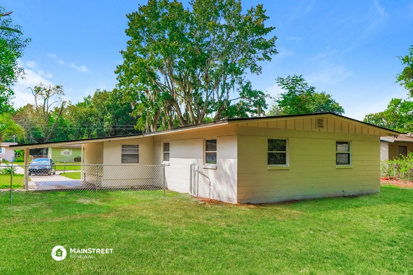 a yellow house with a tree behind it and a fence