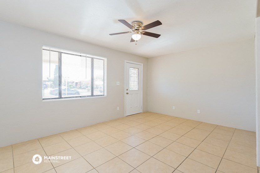 an empty living room with a ceiling fan and a window