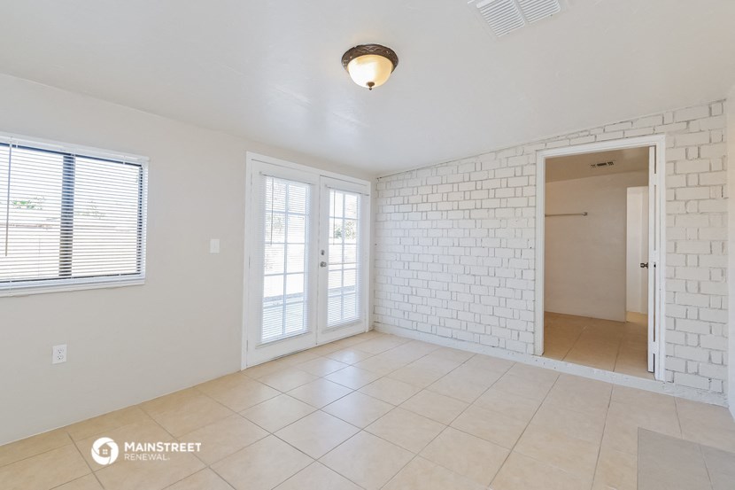 an empty living room with a white brick wall and a door to a hallway