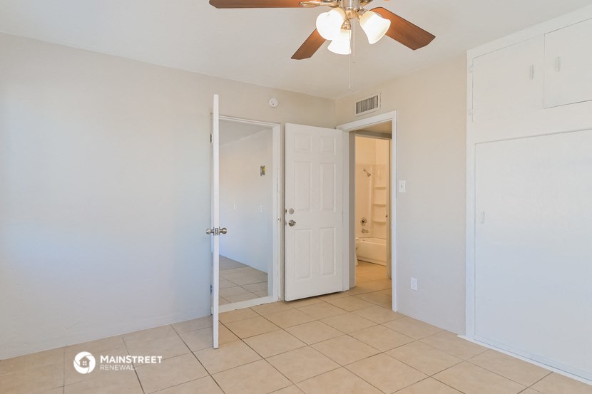 a bedroom with a ceiling fan and a door to a bathroom