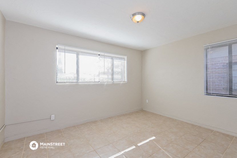 the spacious living room with two windows and a tiled floor