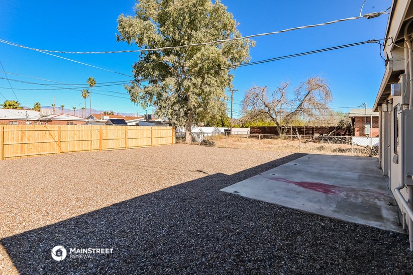an empty yard with a wooden fence and a gravel driveway