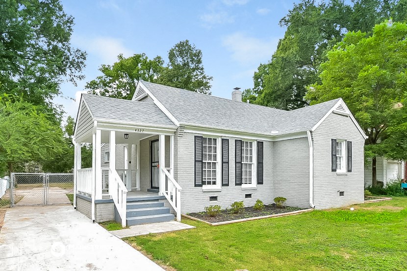 the front of a white house with a porch and a lawn
