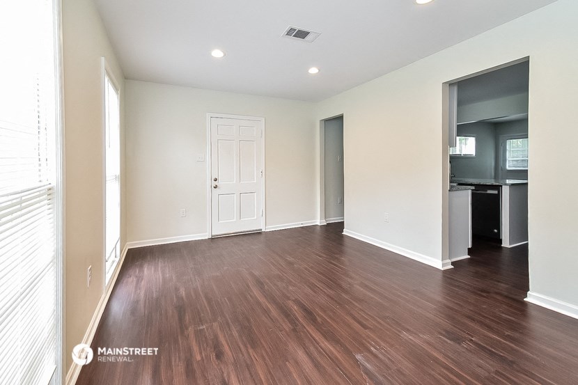 a living room with a hardwood floor and a door to a kitchen