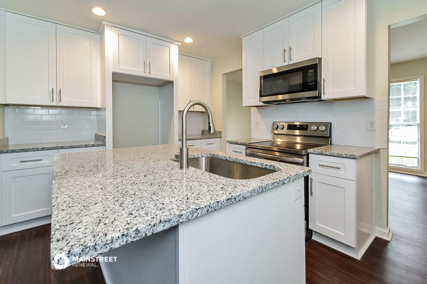 a kitchen with white cabinets and a granite counter top