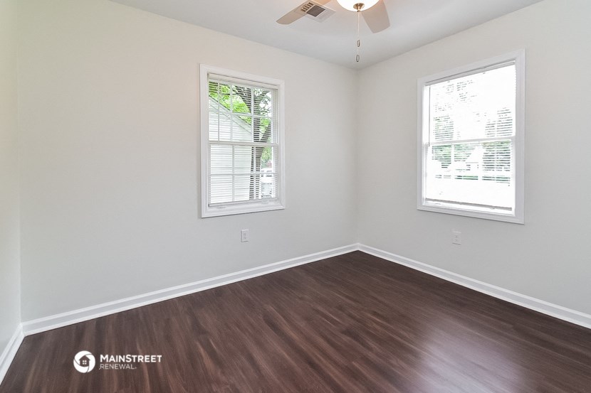 the spacious living room with hardwood flooring and two windows