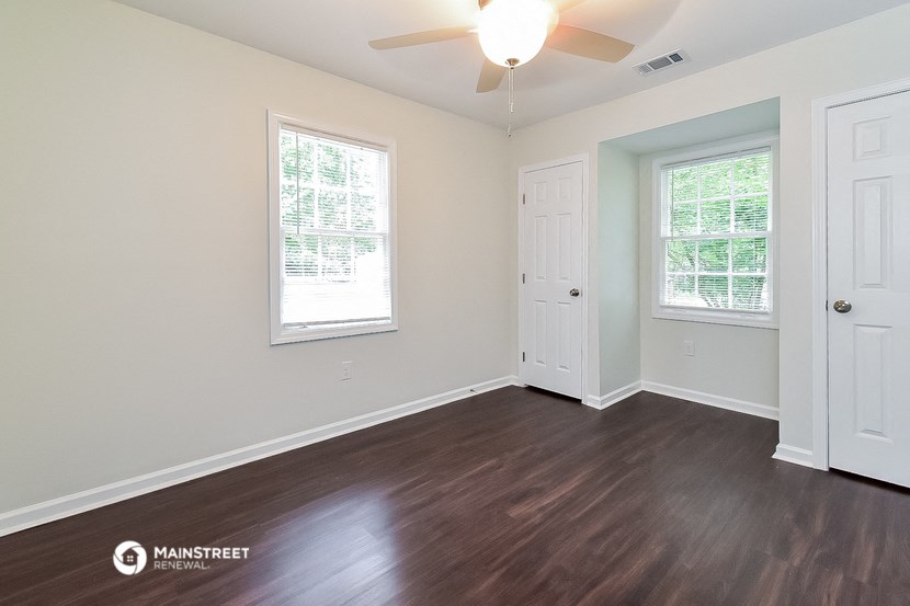 the living room of a house with wood floors and a ceiling fan