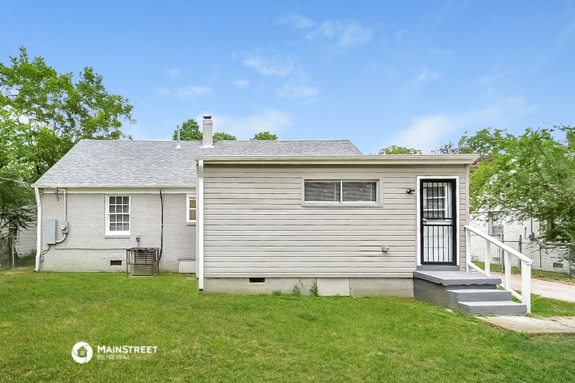 a small white house with a porch and a grassy yard