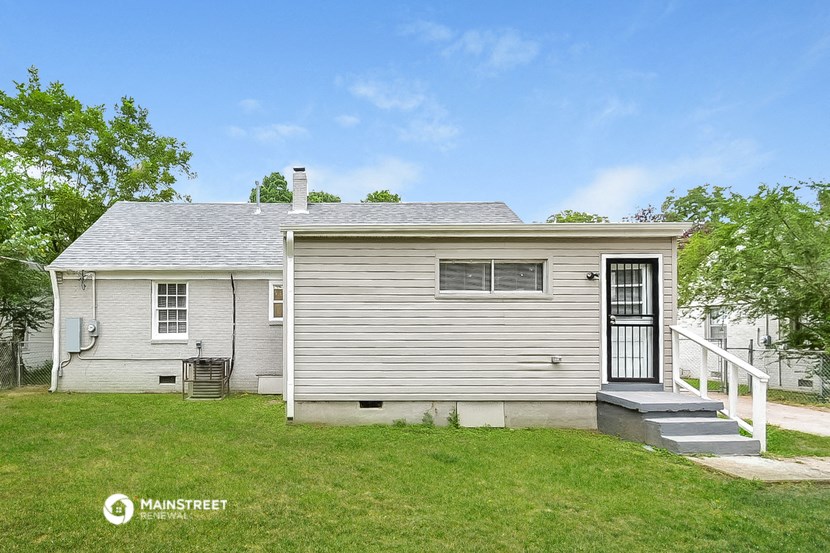 a small white house with a porch and a grassy yard