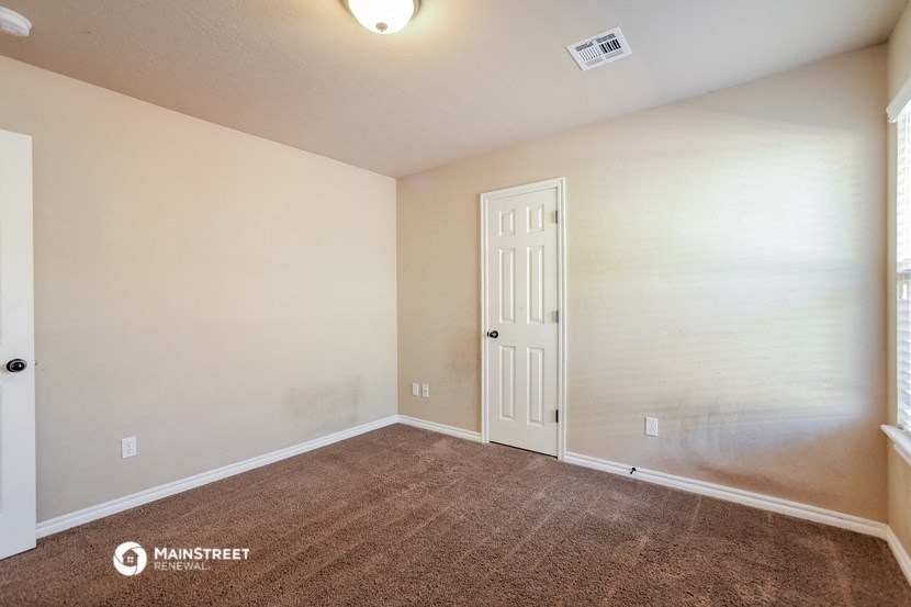 the spacious living room with carpeted flooring and a white door