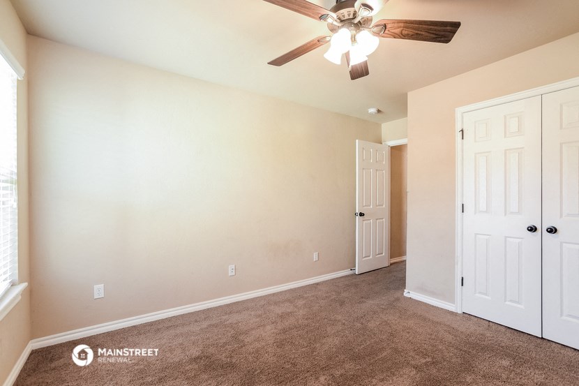 the living room of a home with carpet and a ceiling fan
