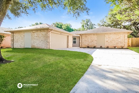 a white brick house with a driveway and lawn