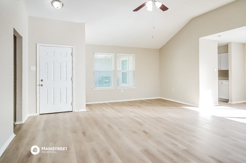 an empty living room with a white door and wood flooring