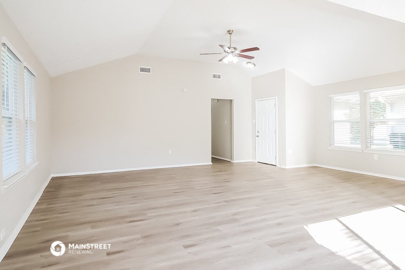 an empty living room with white walls and a ceiling fan