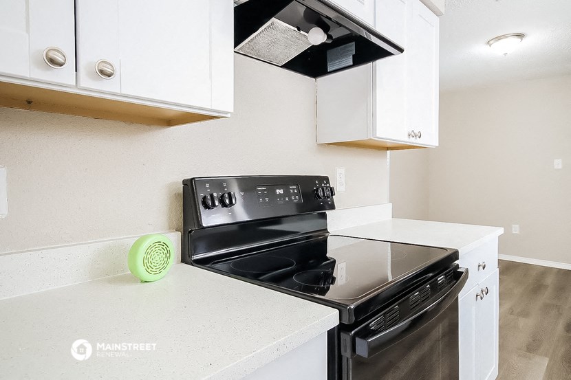 a kitchen with white cabinets and a black stove