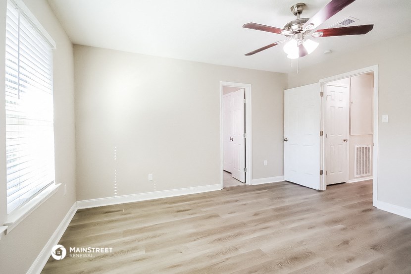 a living room with white walls and a ceiling fan
