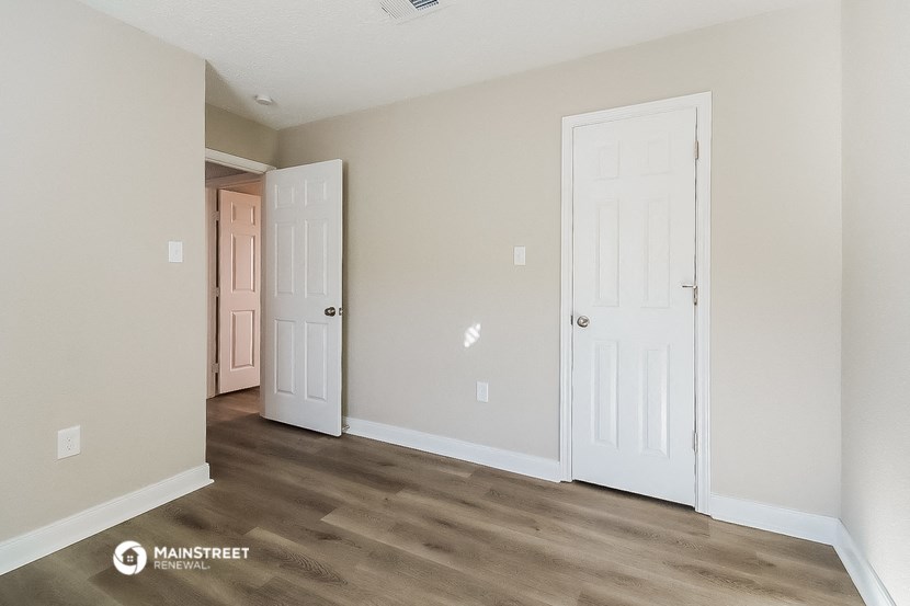 a bedroom with two doors and a door to a closet