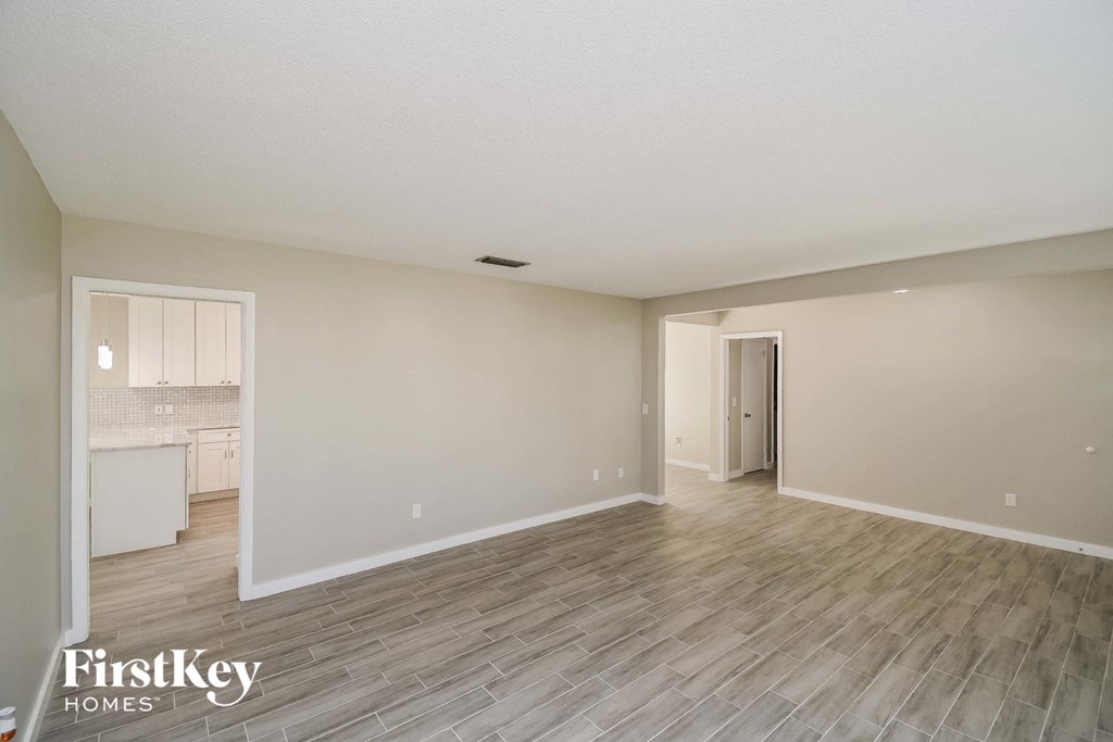 A spacious room with wooden flooring and a doorway leading to another room.