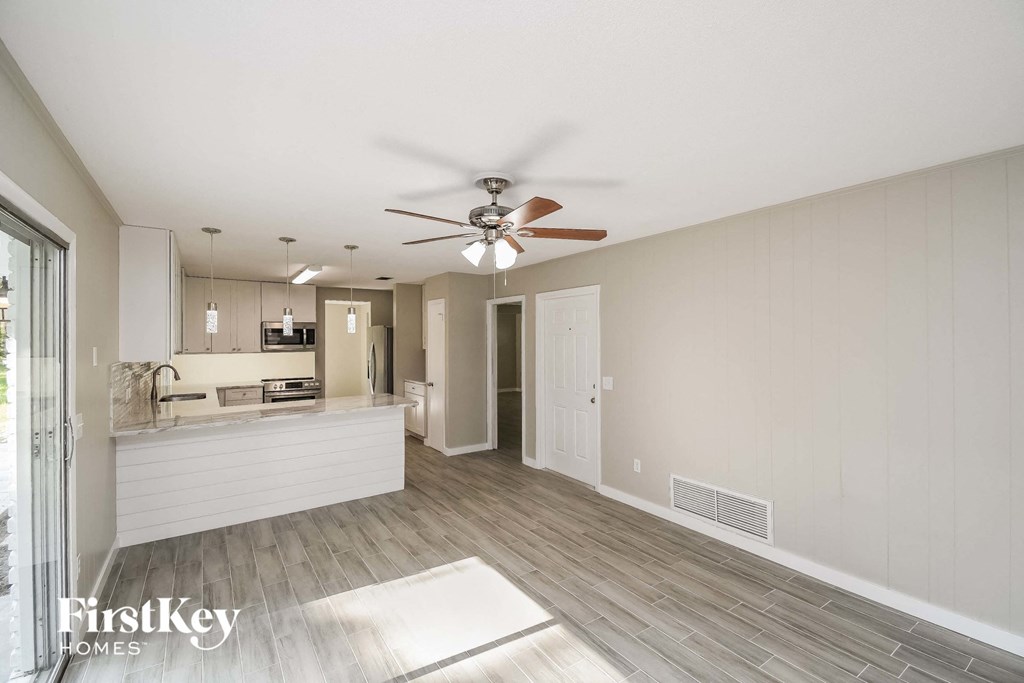A spacious room with a ceiling fan and a rug on the floor.