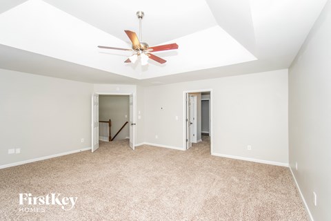 a spacious living room with carpet and a ceiling fan