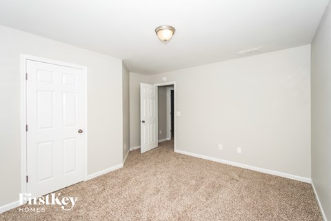 a master bedroom with carpet and a door to a closet