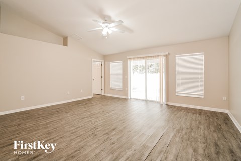 A spacious room with wooden flooring and a ceiling fan.