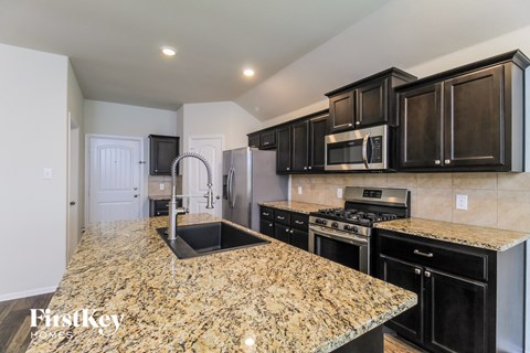 a kitchen with black cabinets and granite counter tops and a sink