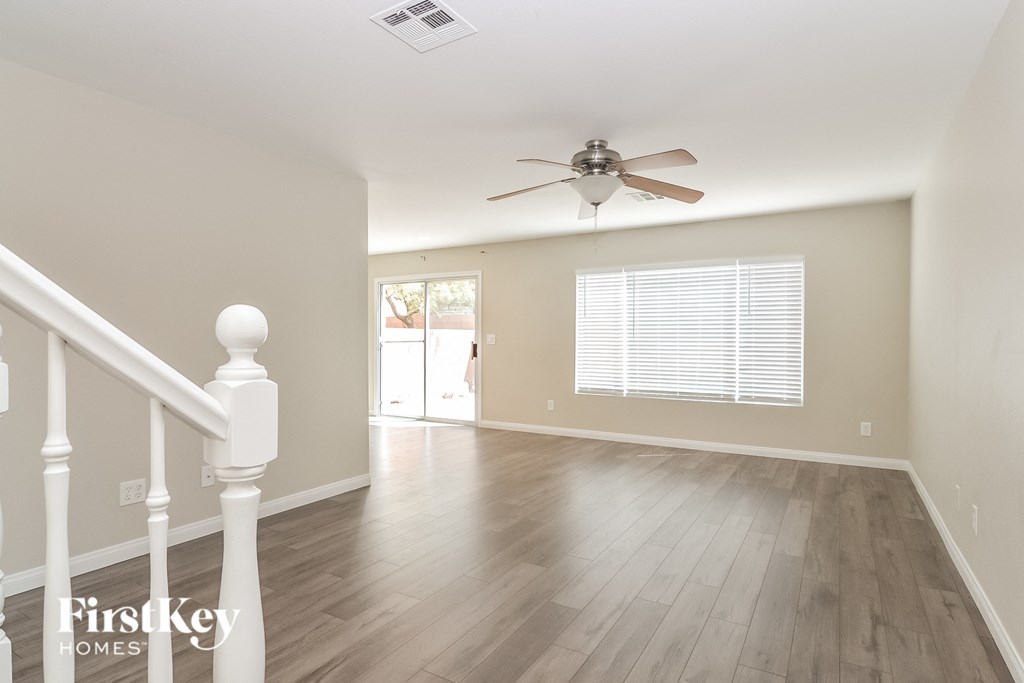 the living room and dining room with wood floors and a ceiling fan