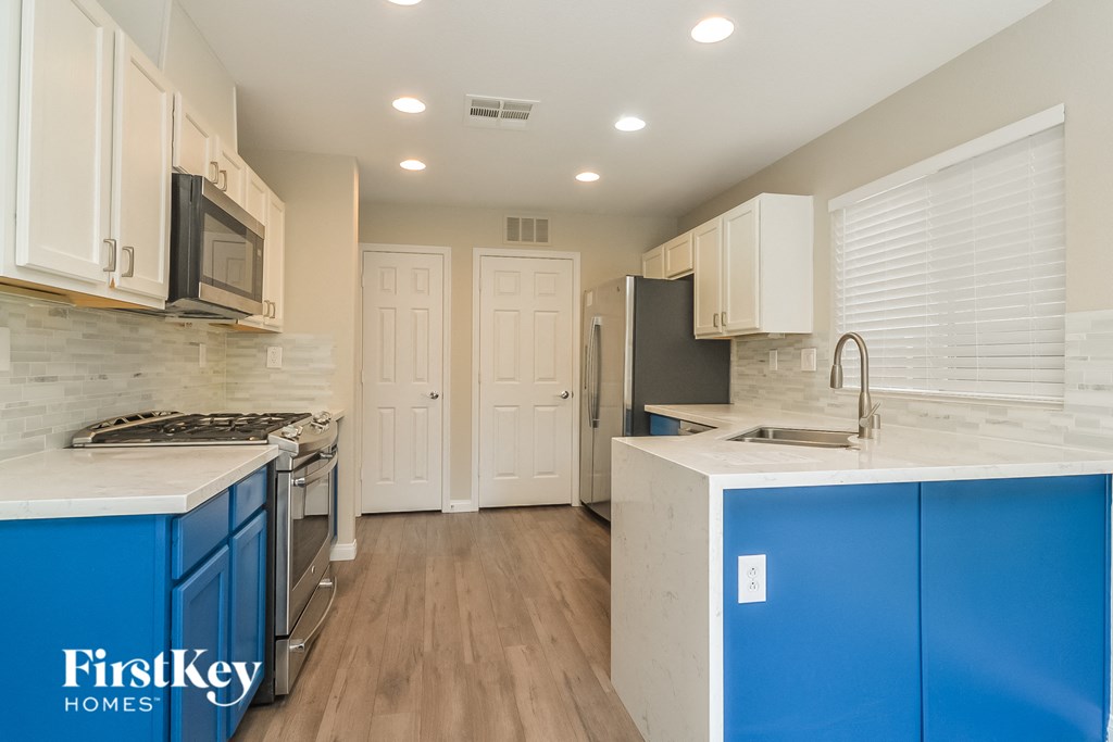 a kitchen with blue and white cabinets and a stainless steel refrigerator